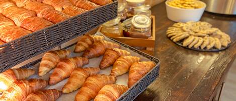 A variety of baked goods including croissants and pastries displayed in baskets and on trays.