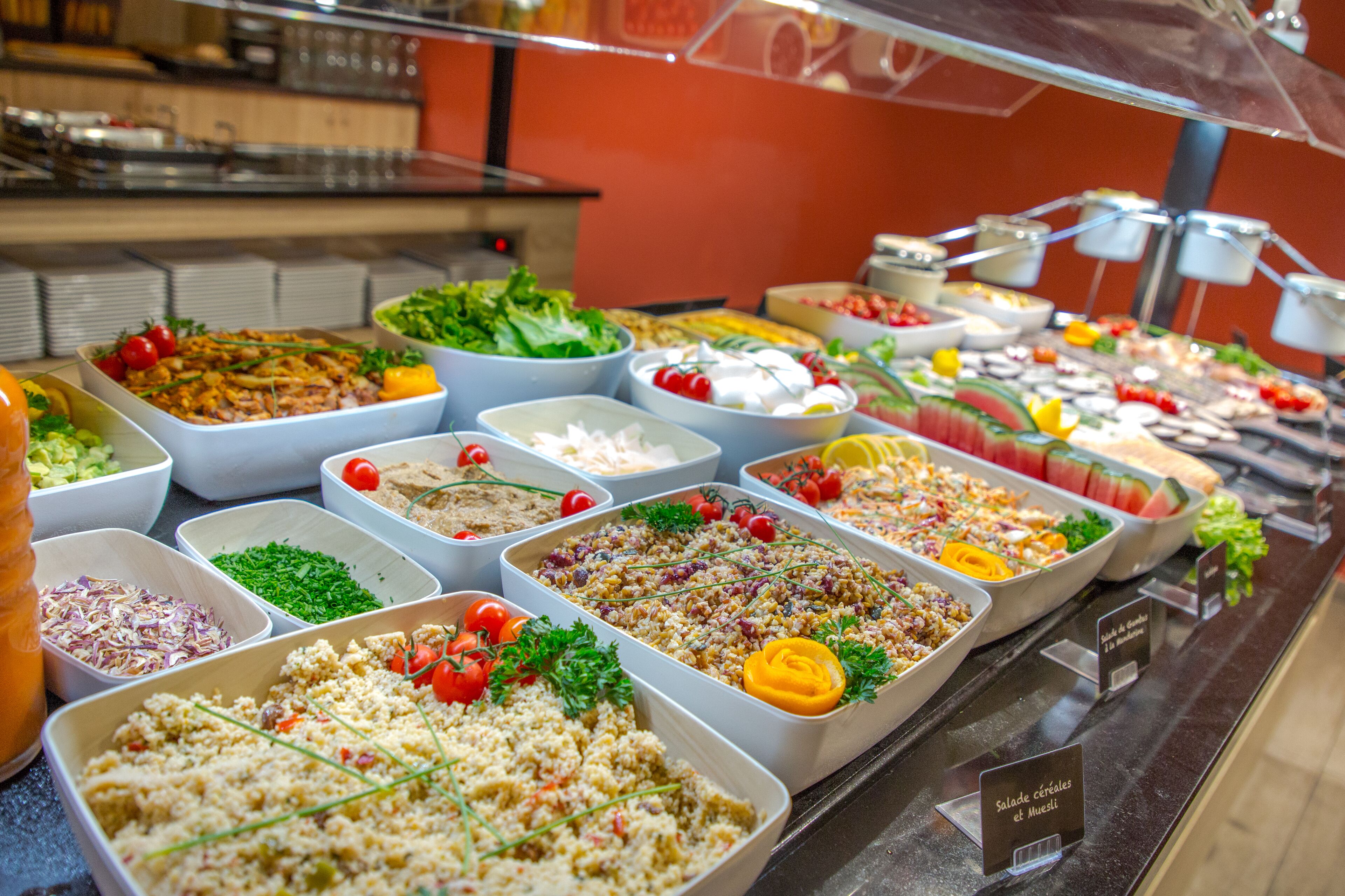 A buffet with various dishes including salads, fruits, and other food items.