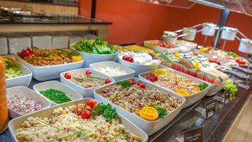 A buffet with various dishes including salads, fruits, and other food items.