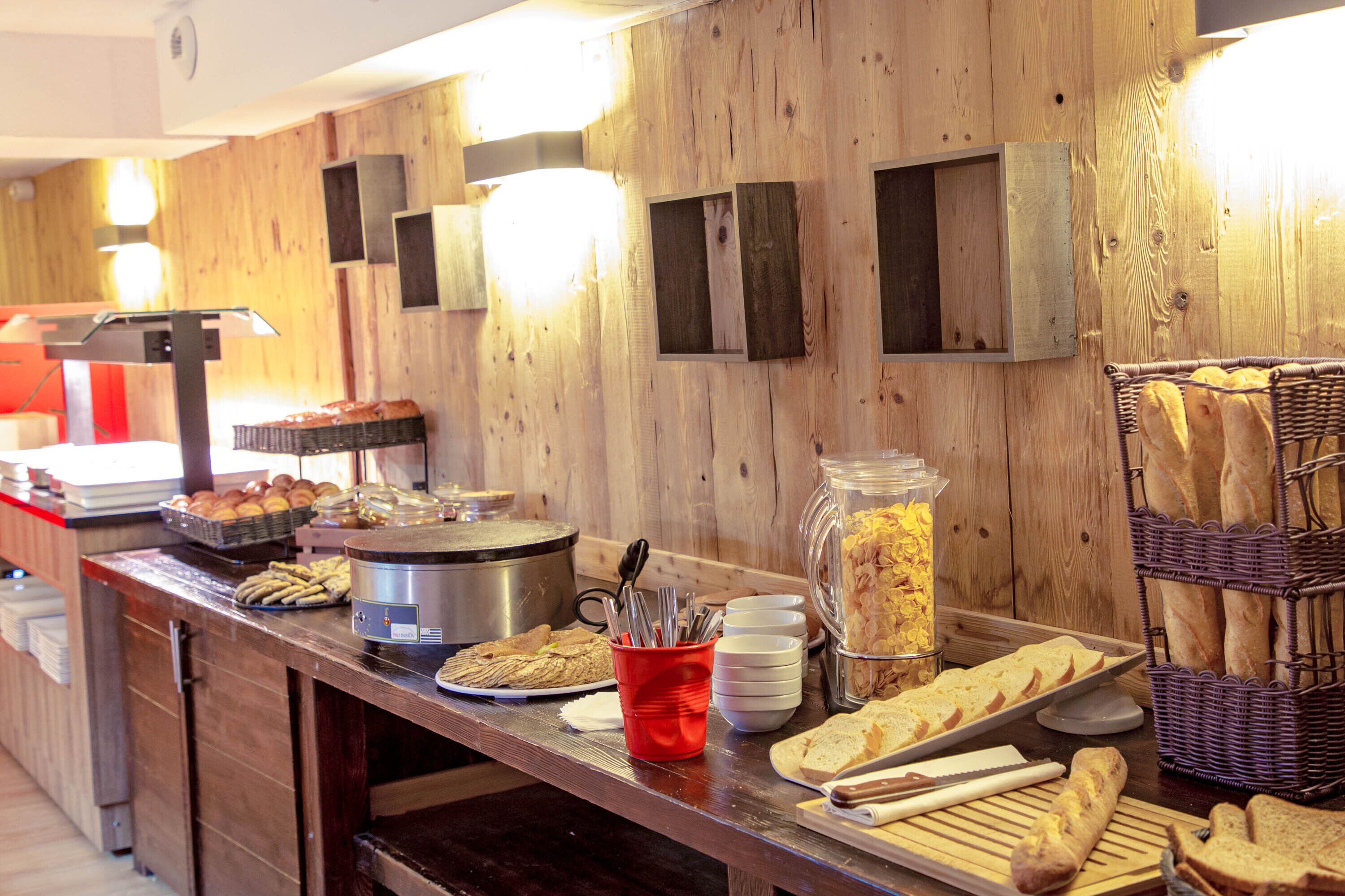 Un buffet proposant une variété de plats, notamment du pain, des pâtisseries et un espace dédié aux plats chauds.