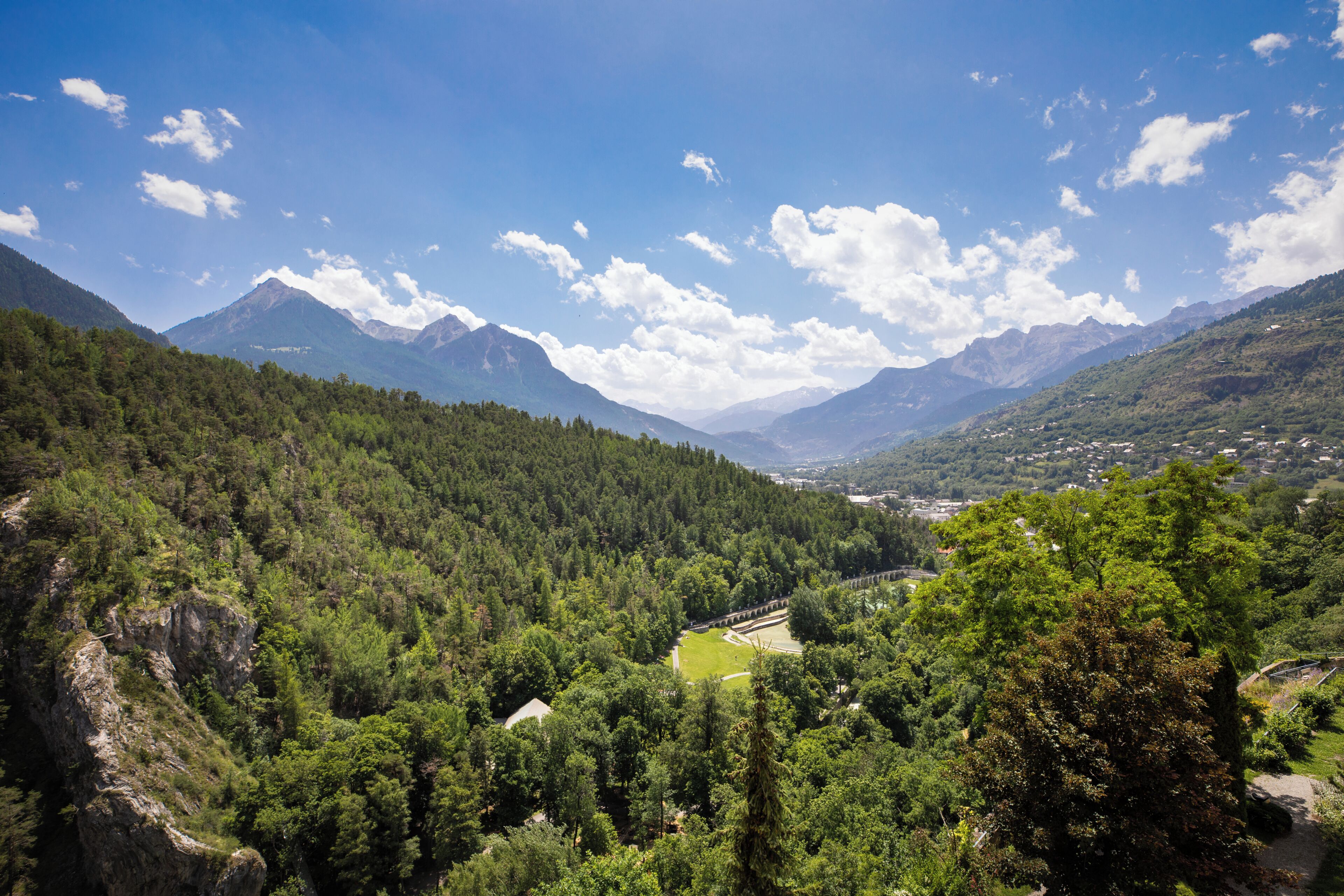 Paisatge de muntanya amb boscos densos, cel serè i muntanyes allunyades.
