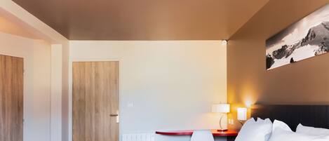 A hotel room with a bed, a desk, a chair, a lamp, and a wall-mounted picture.