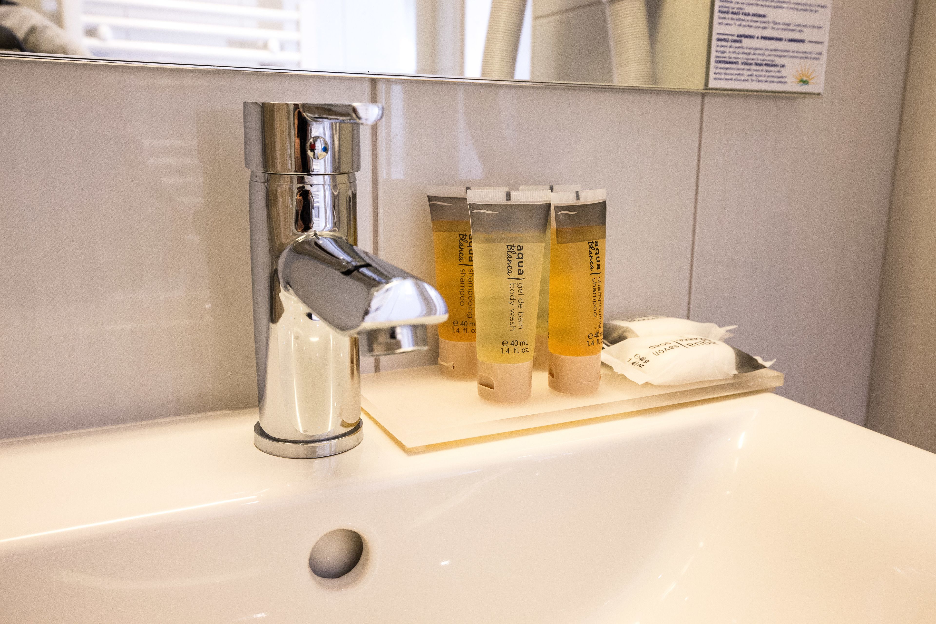 A bathroom sink with a modern faucet and three bottles of lotion on the counter.