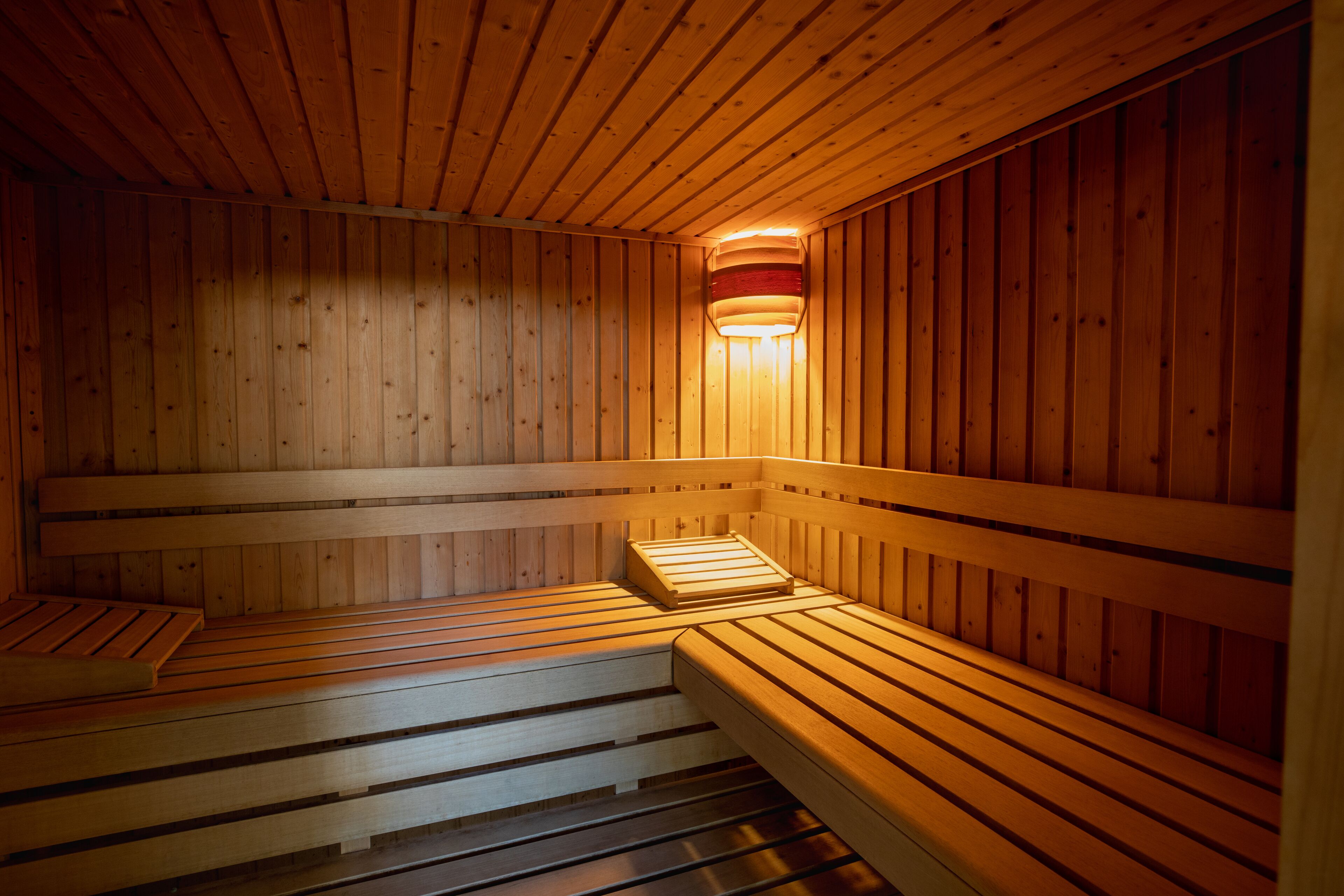 Eine Sauna mit Holzbänken und einer an der Wand befestigten Leuchte.