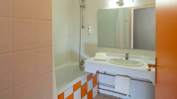 Een badkamer met een bad, een wastafel en een spiegel.