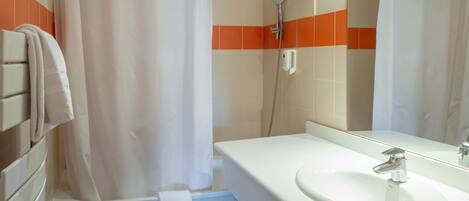 A bathroom with a white sink, a mirror, and a shower.