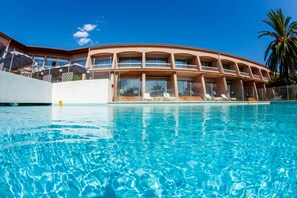 Un hôtel doté d’une piscine, de plusieurs balcons et de chaises longues.