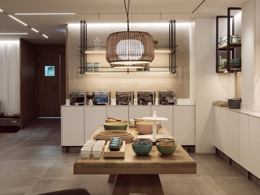 Une cuisine moderne dotée d’un îlot central, d’étagères intégrées et d’un luminaire suspendu.