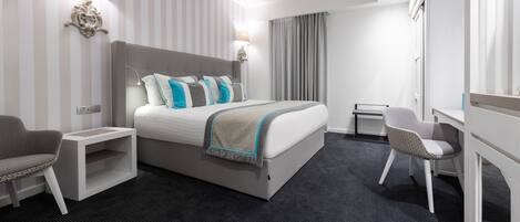 A modern hotel room with a large bed, bedside tables, a desk, and a chair.