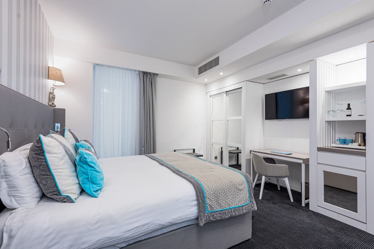 Ein modernes Hotelzimmer mit einem großen Bett, einem Schreibtisch und einem Fernseher.