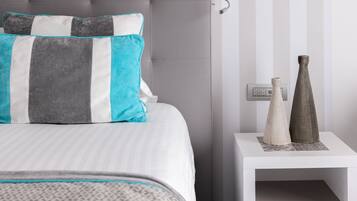 A neatly arranged hotel room with a bed, a bedside lamp, and a nightstand with decorative items.