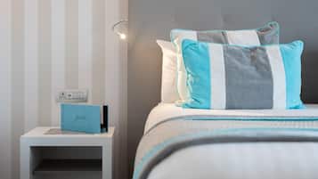 A neatly made bed with striped pillows, a bedside table with a blue folder, and a wall with vertical stripes.