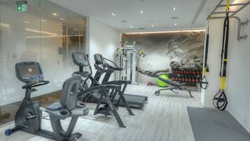 Uma academia moderna com máquinas de cardio, um suporte de pesos na parede e um tapete de yoga.