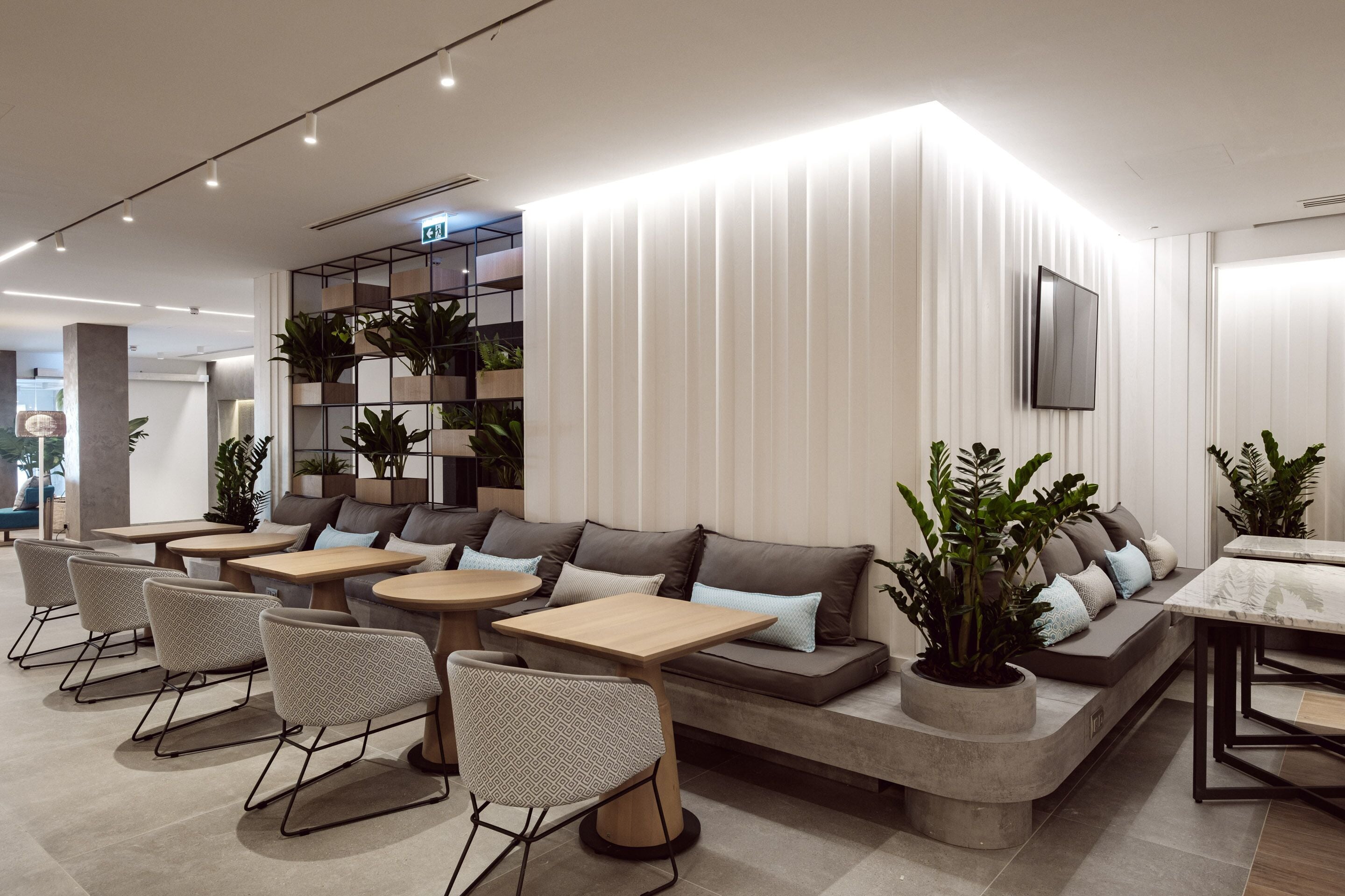 Un espace de détente moderne, doté de sièges, de tables et de plantes en pot.