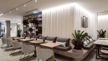 Un espace de détente moderne, doté de sièges, de tables et de plantes en pot.