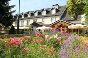 A hotel with multiple balconies, a garden with colorful flowers, and outdoor seating areas. - Hotel & Restaurant Eurohof (Duisburg)