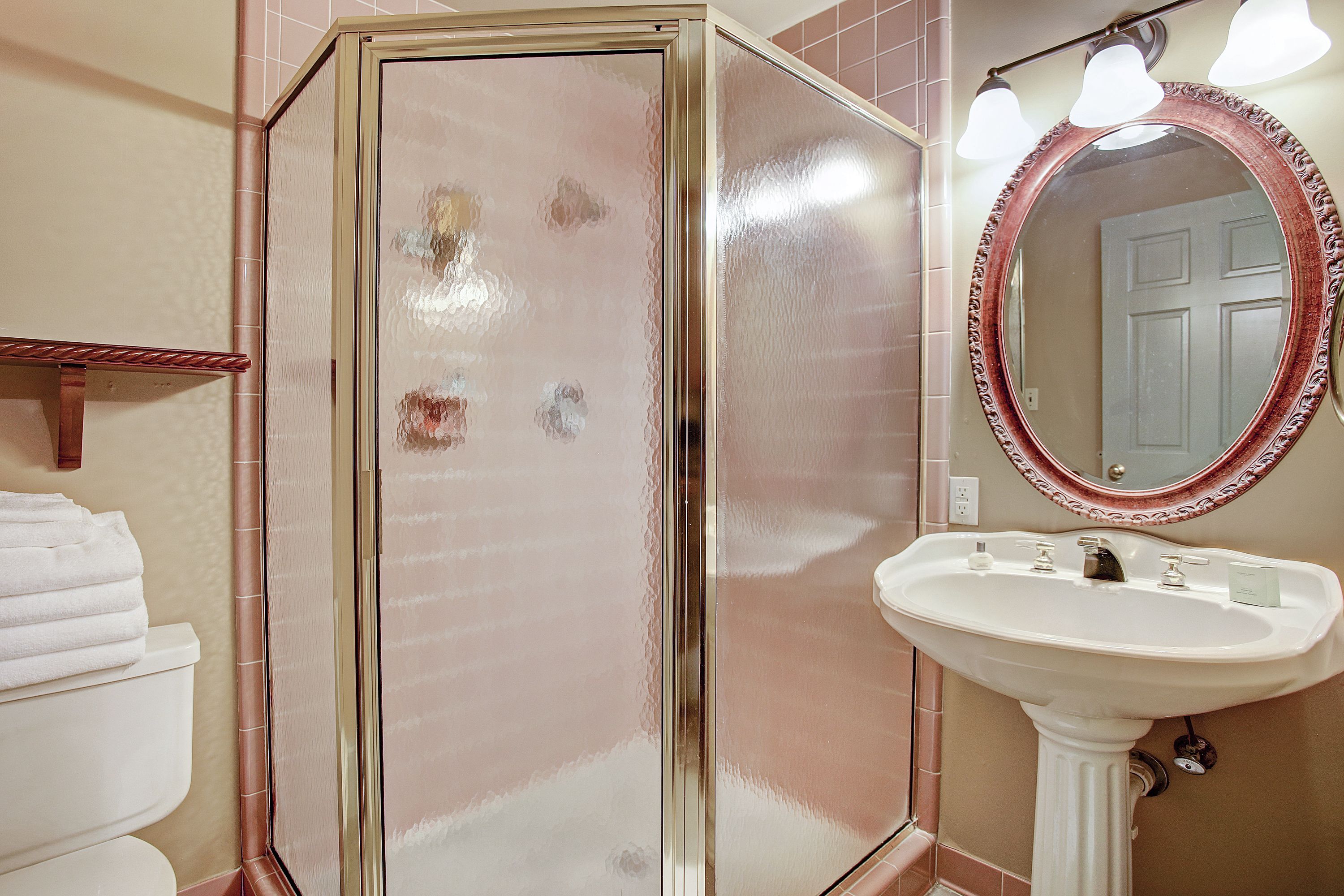 A bathroom with a glass shower enclosure, a sink with a mirror, and a towel rack.