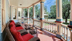 Une véranda avec des meubles en osier et une balustrade.