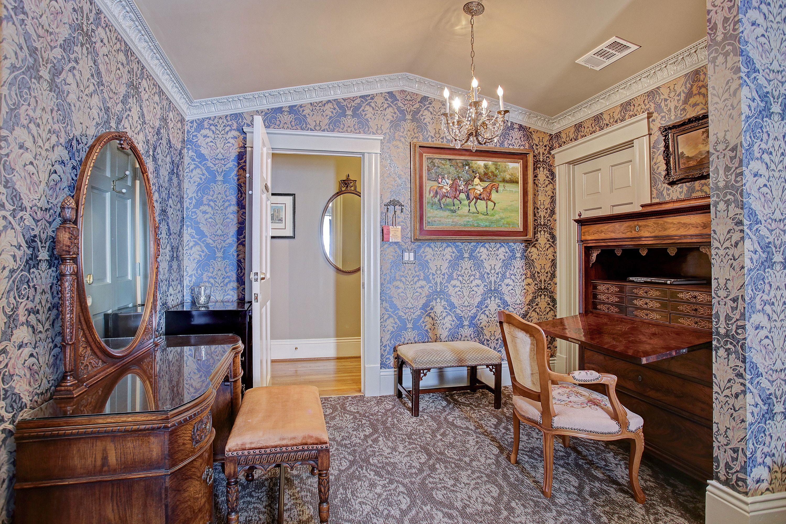 A room with a large mirror, a wooden desk, a chair, and a fireplace.