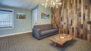 Un salon avec un canapé gris, une table basse en bois et un lustre.