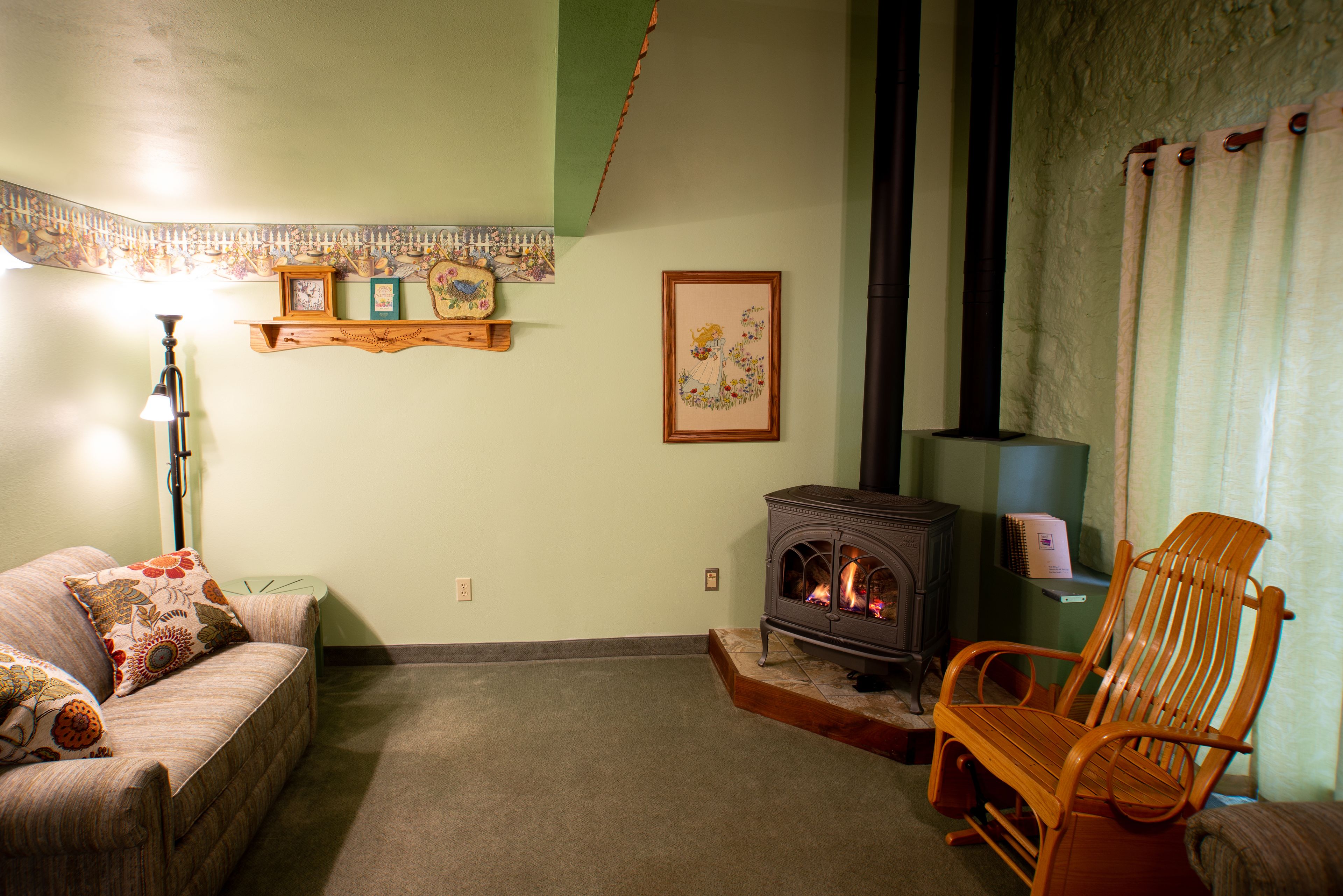 Un salón acogedor con un sofá, una silla de madera, una chimenea y adornos en la pared.