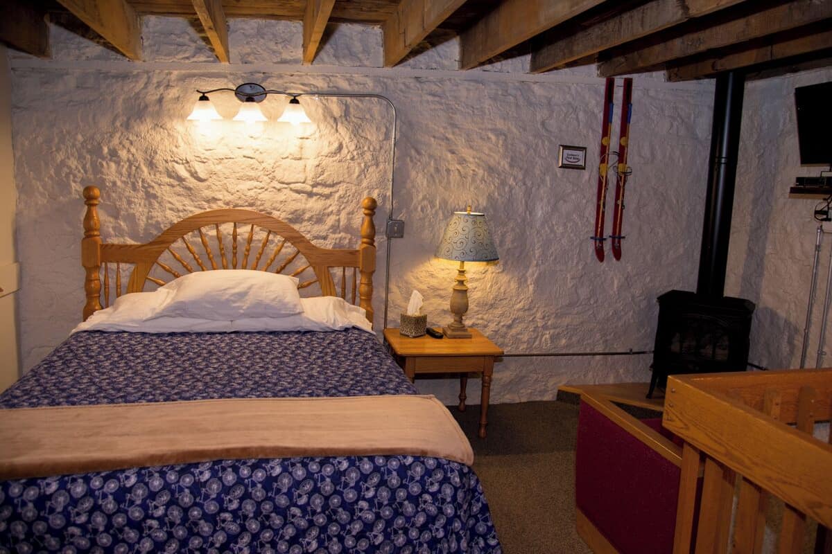 A cozy room with a wooden bed, a lamp, and a fireplace.