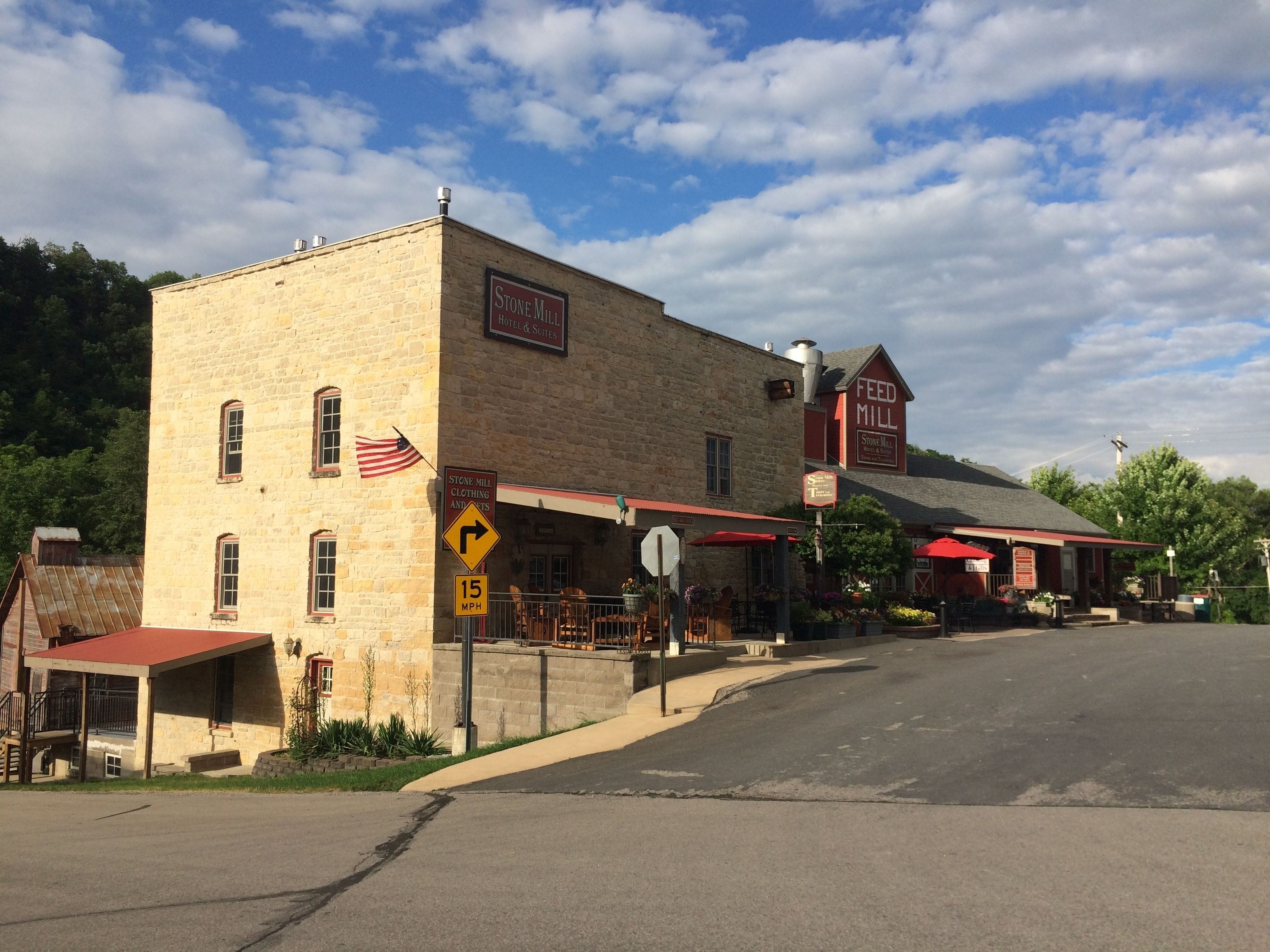 A historic stone building with a sign for Stone Mill Hotel & Suites.