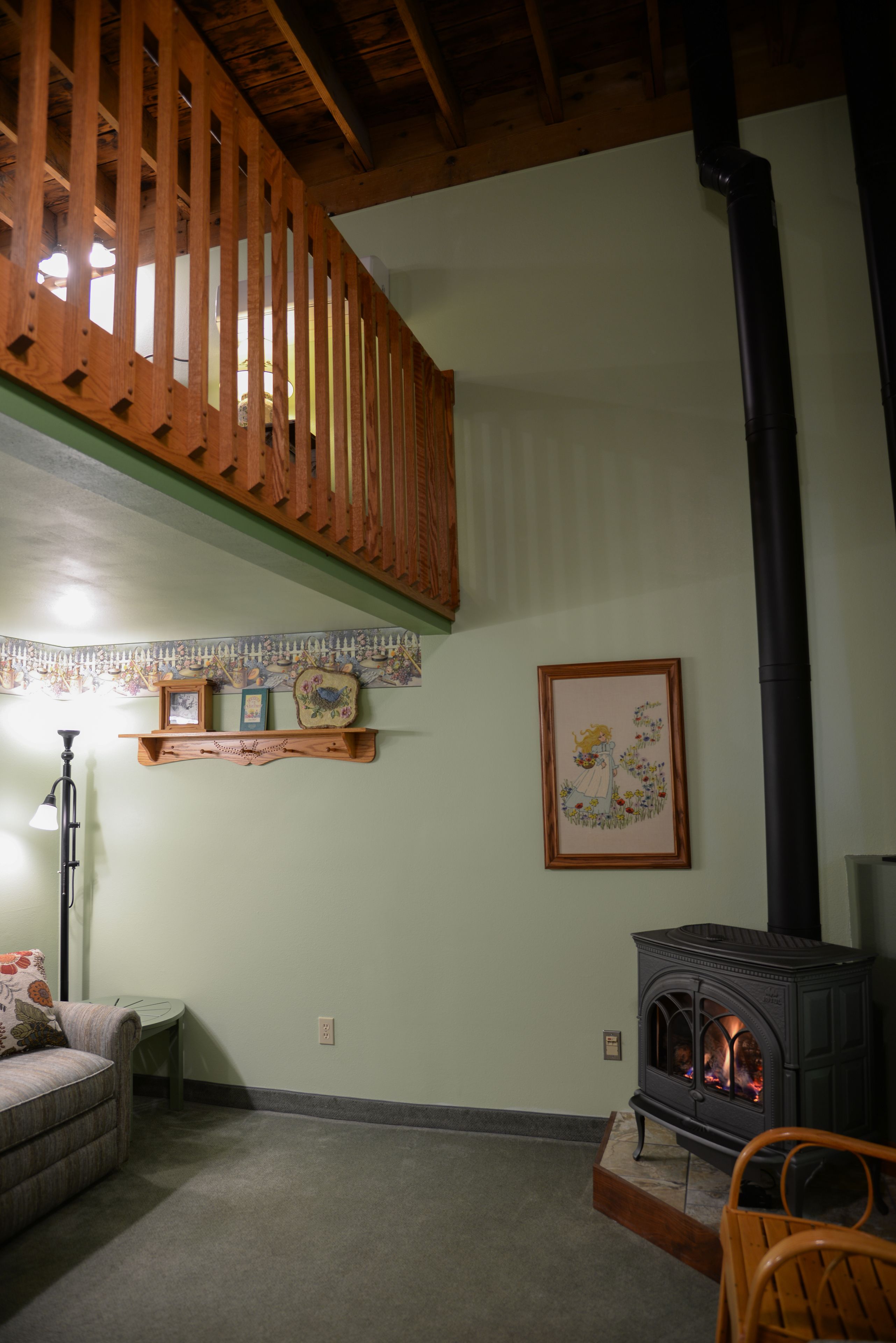 A cozy living room with a fireplace, wooden furniture, and a decorative wall.