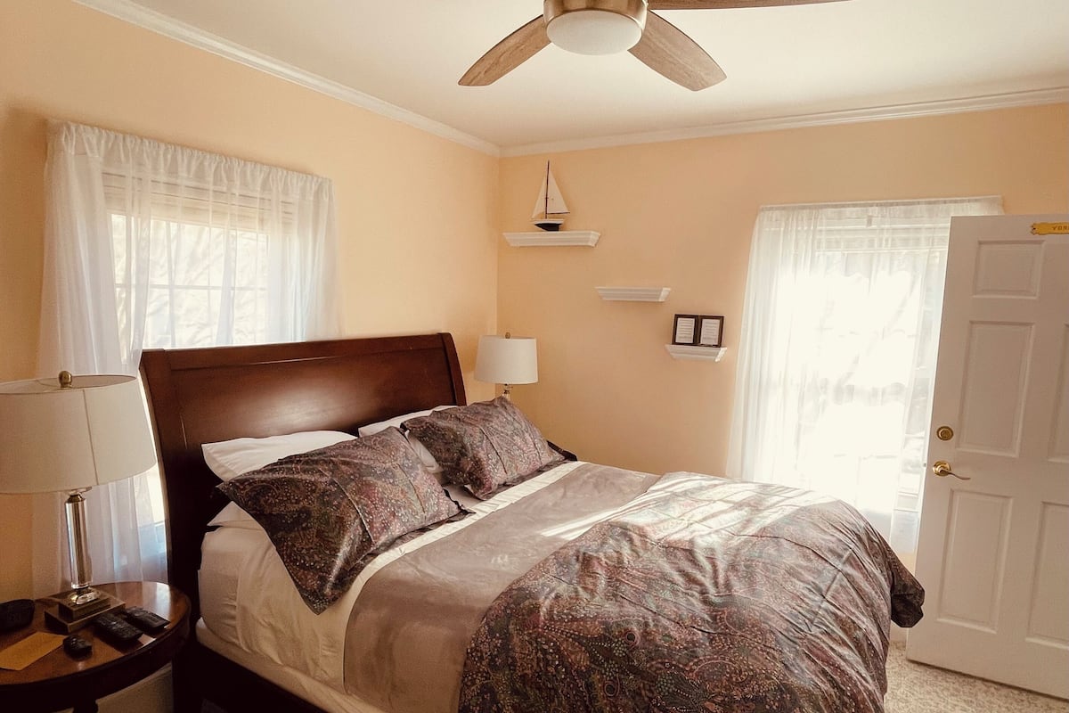 A neatly made bed with a patterned bedspread, a wooden headboard, and a bedside table with a lamp.