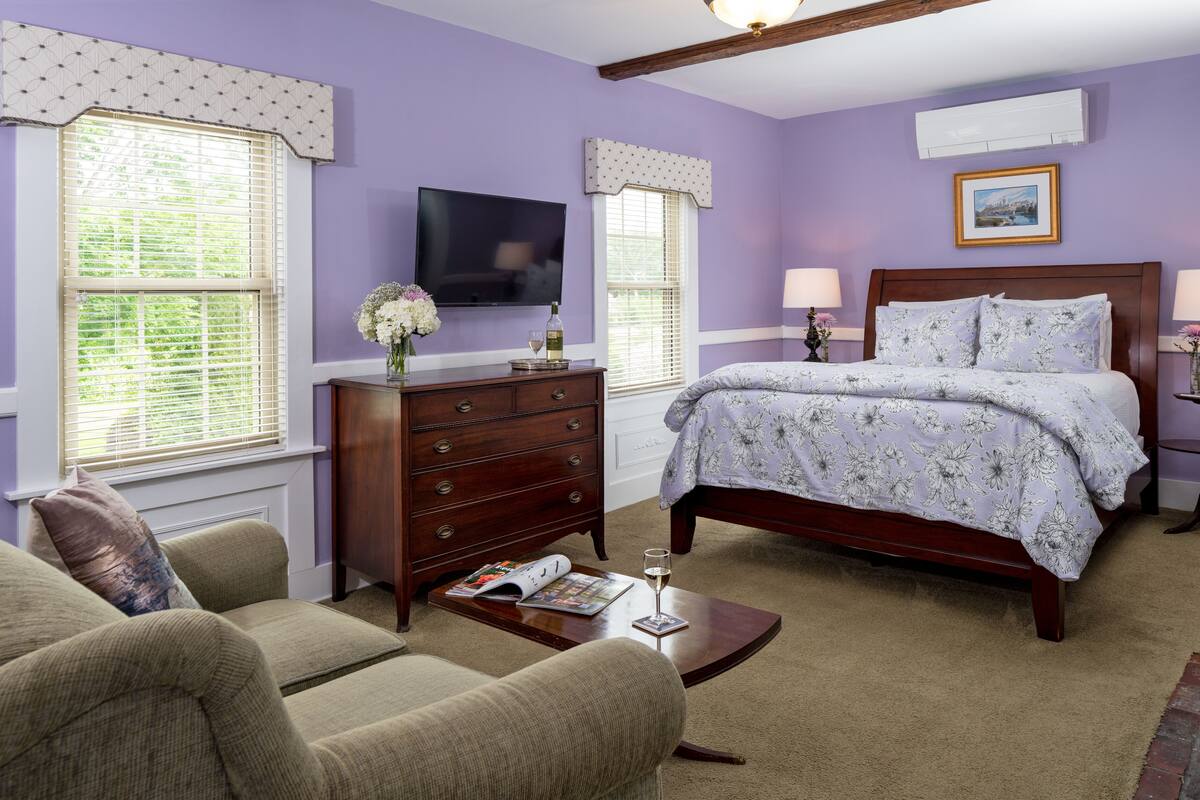 A bedroom with a bed, dresser, TV, and two lamps.