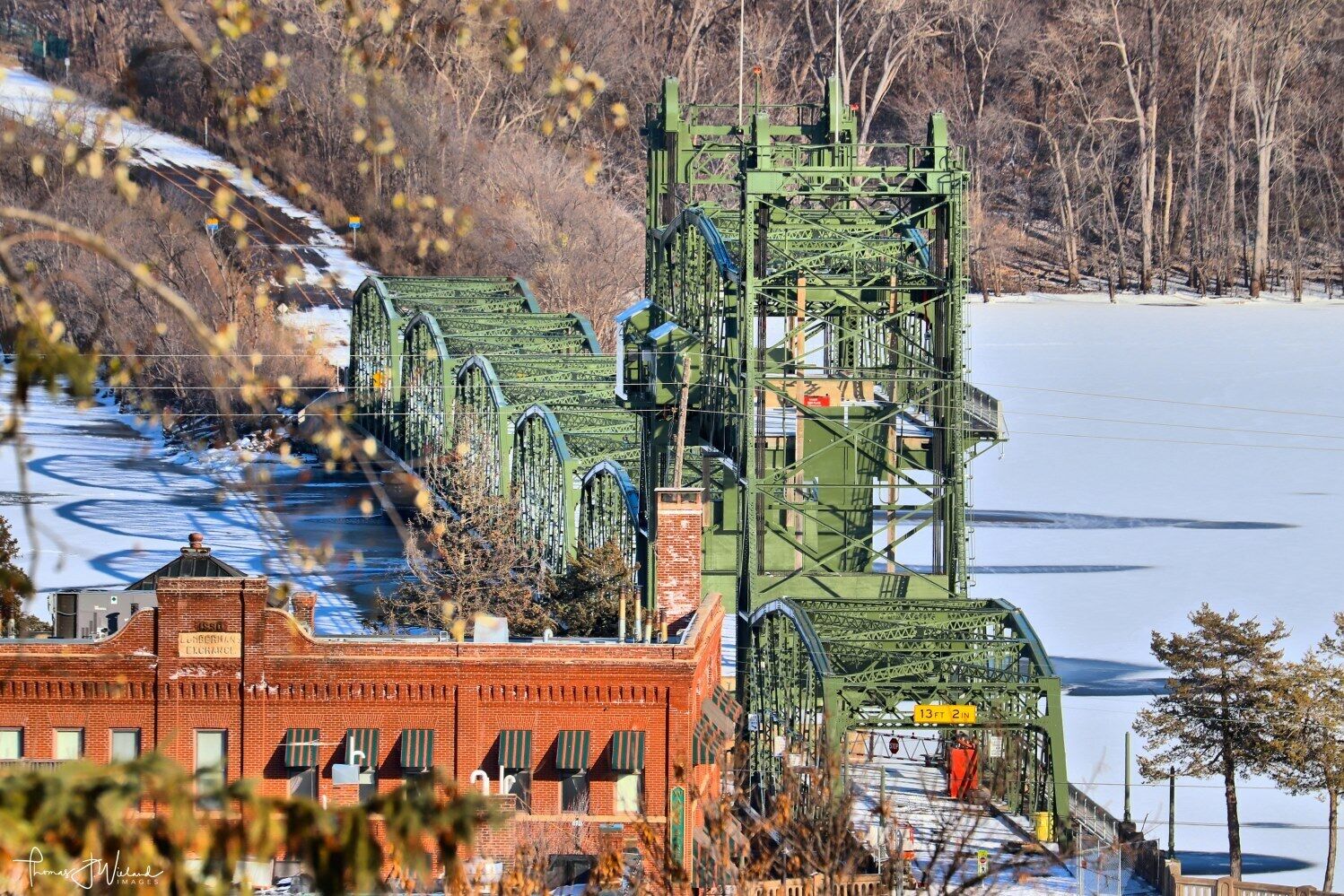 A large green metal structure with a brick building in the foreground.