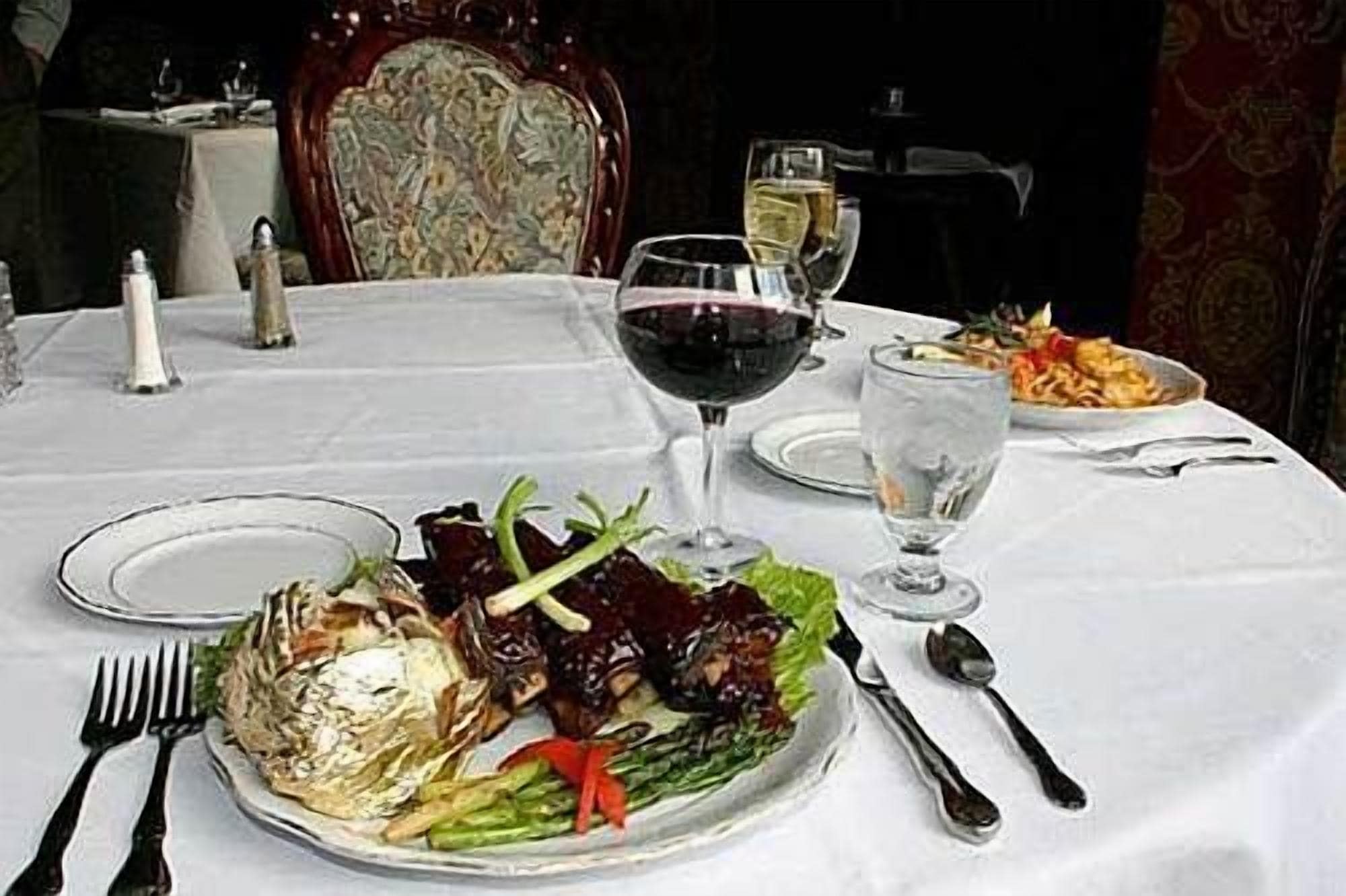 A dining table with a plate of food, a glass of red wine, and a glass of water.