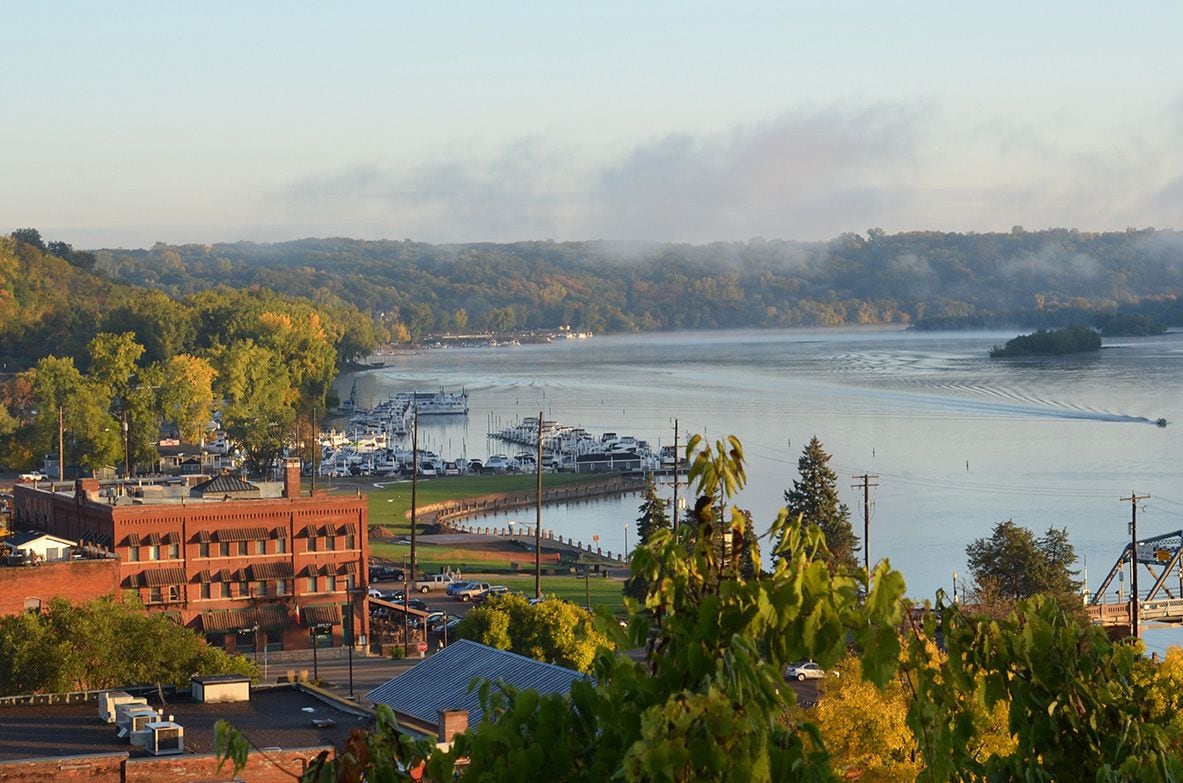 A marina with boats, a bridge, and a forested hillside.