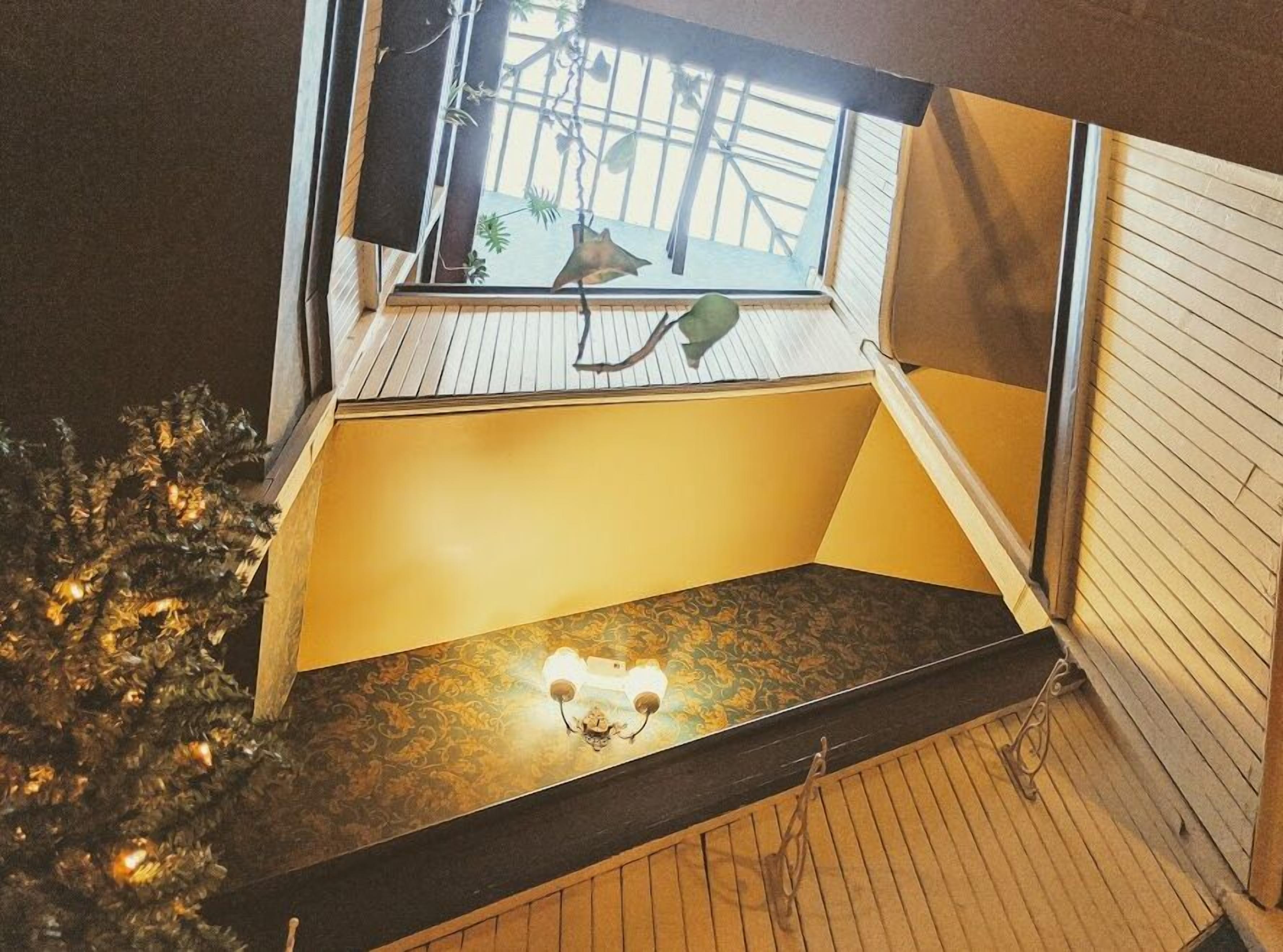 Une pièce avec un plafond en pente, une fenêtre donnant sur le ciel et un petit balcon doté d’une balustrade.