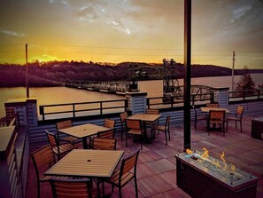 An outdoor patio with tables and chairs, overlooking a body of water and a bridge. - Water Street Inn (Stillwater)