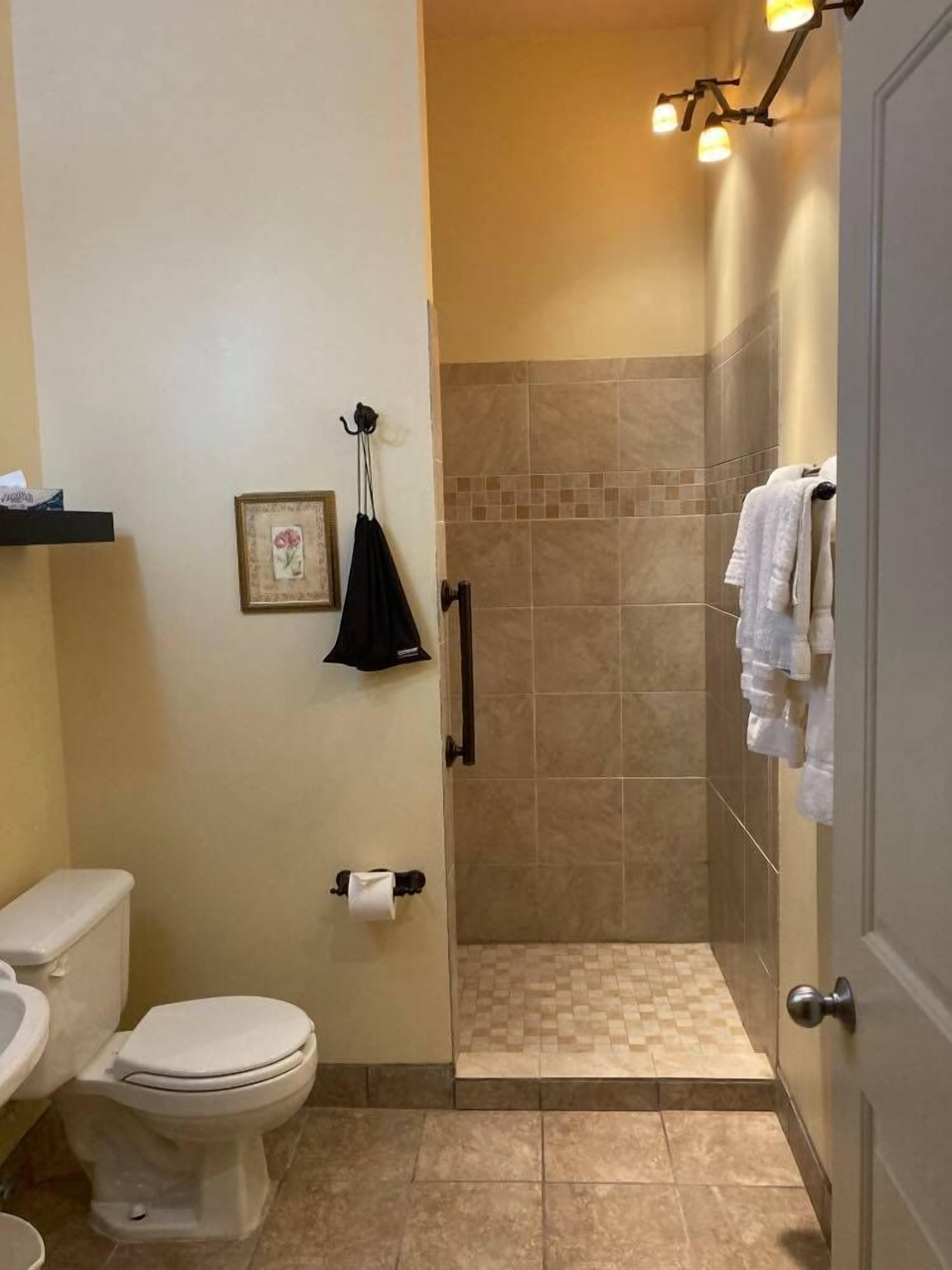 A bathroom with a toilet, sink, and shower area.