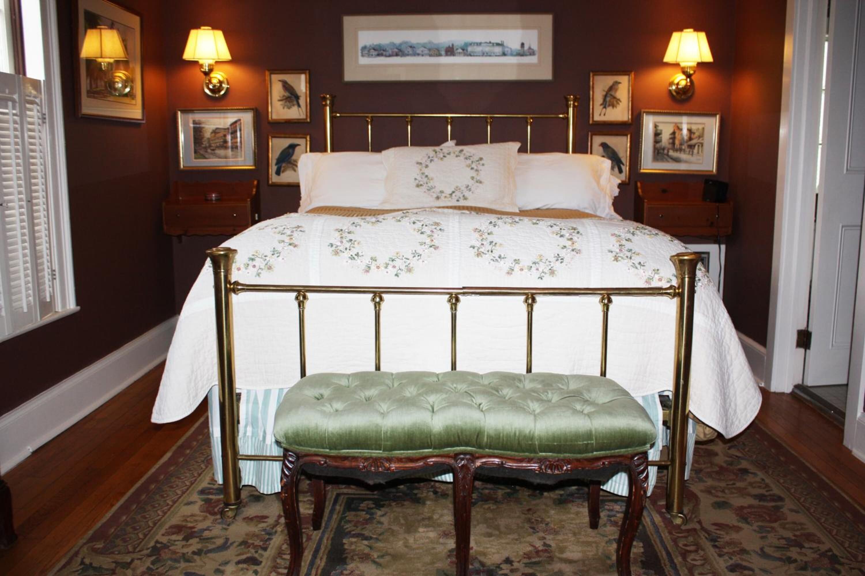 A bedroom with a four-poster bed, a green upholstered bench, and a patterned bedspread.