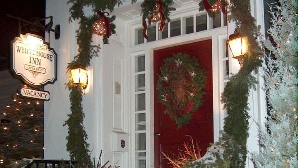 A hotel entrance with a red door, a sign indicating vacancy, and Christmas decorations. - The White House Inn (Cooperstown)
