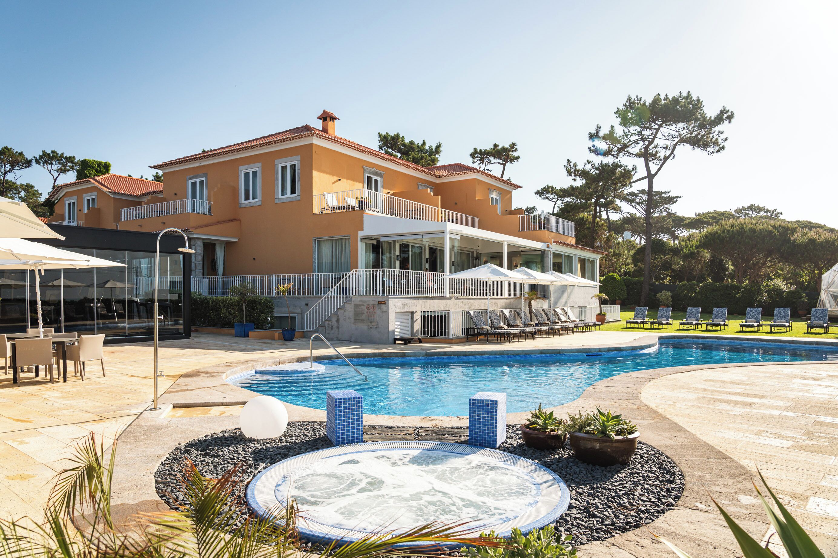 Una casa grande con piscina, mobiliario exterior y bañera de hidromasaje.