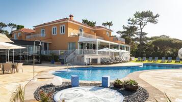 Una casa grande con piscina, mobiliario exterior y bañera de hidromasaje.