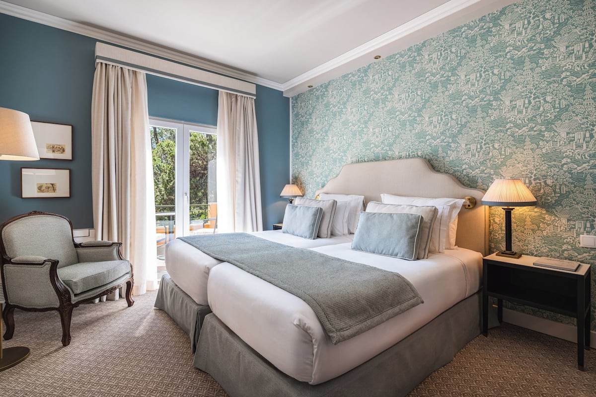A bedroom with a large bed, two bedside tables, a chair, and a window with curtains.