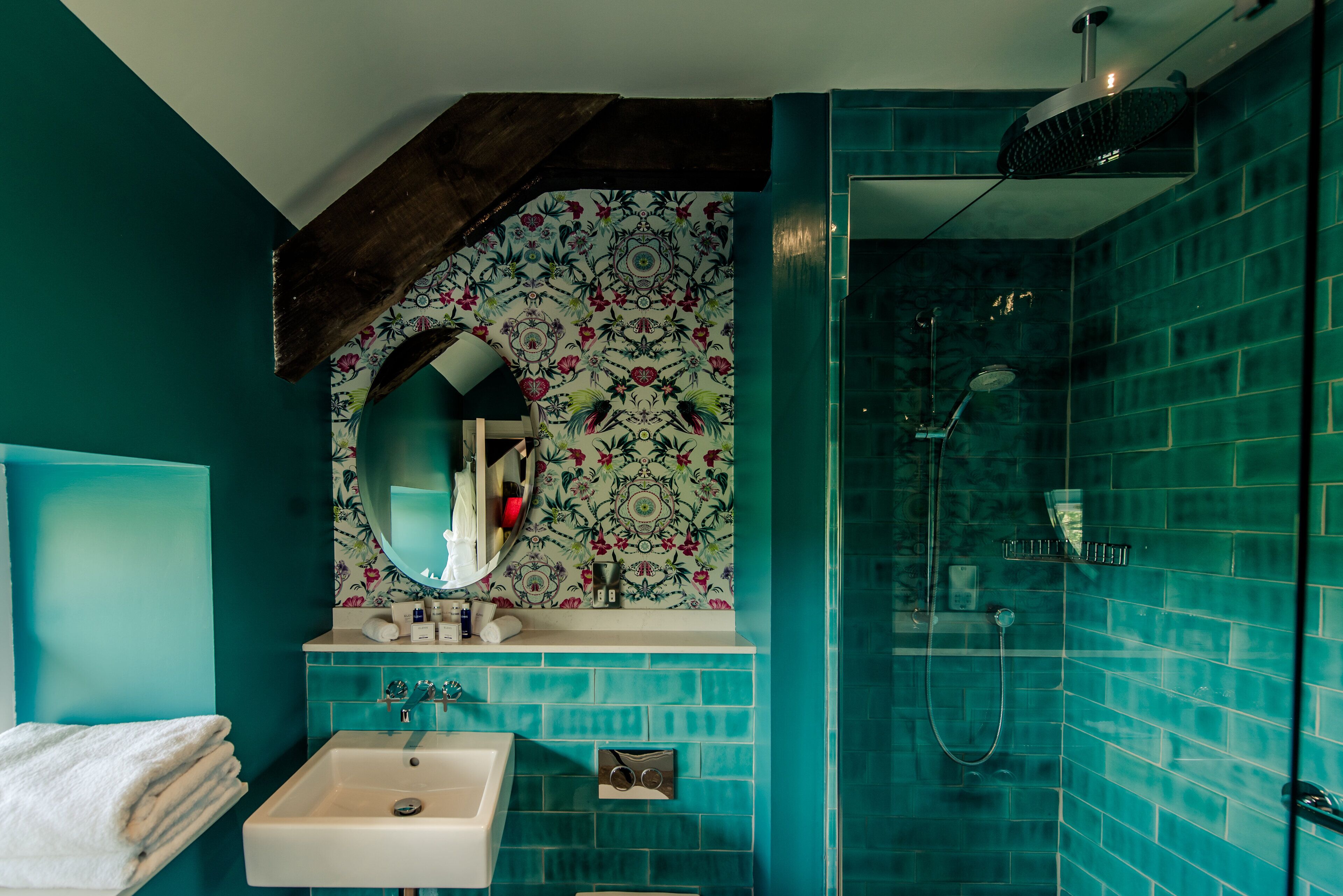 A bathroom with a sink, mirror, and shower.