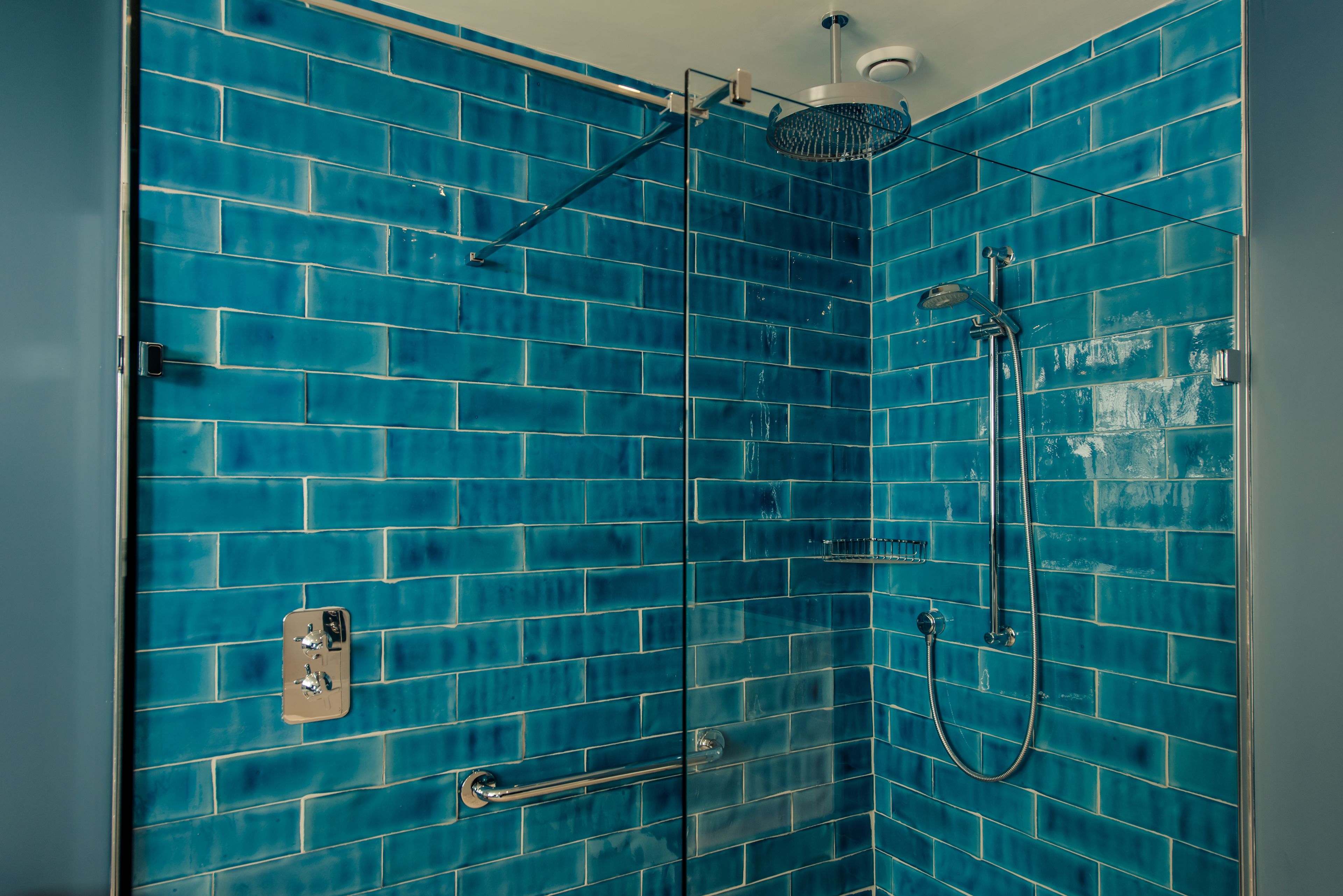 A shower with blue-tiled walls and a glass door.