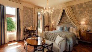 Un dormitorio con una cama grande, una araña, una mesa de comedor con sillas y vistas al exterior.