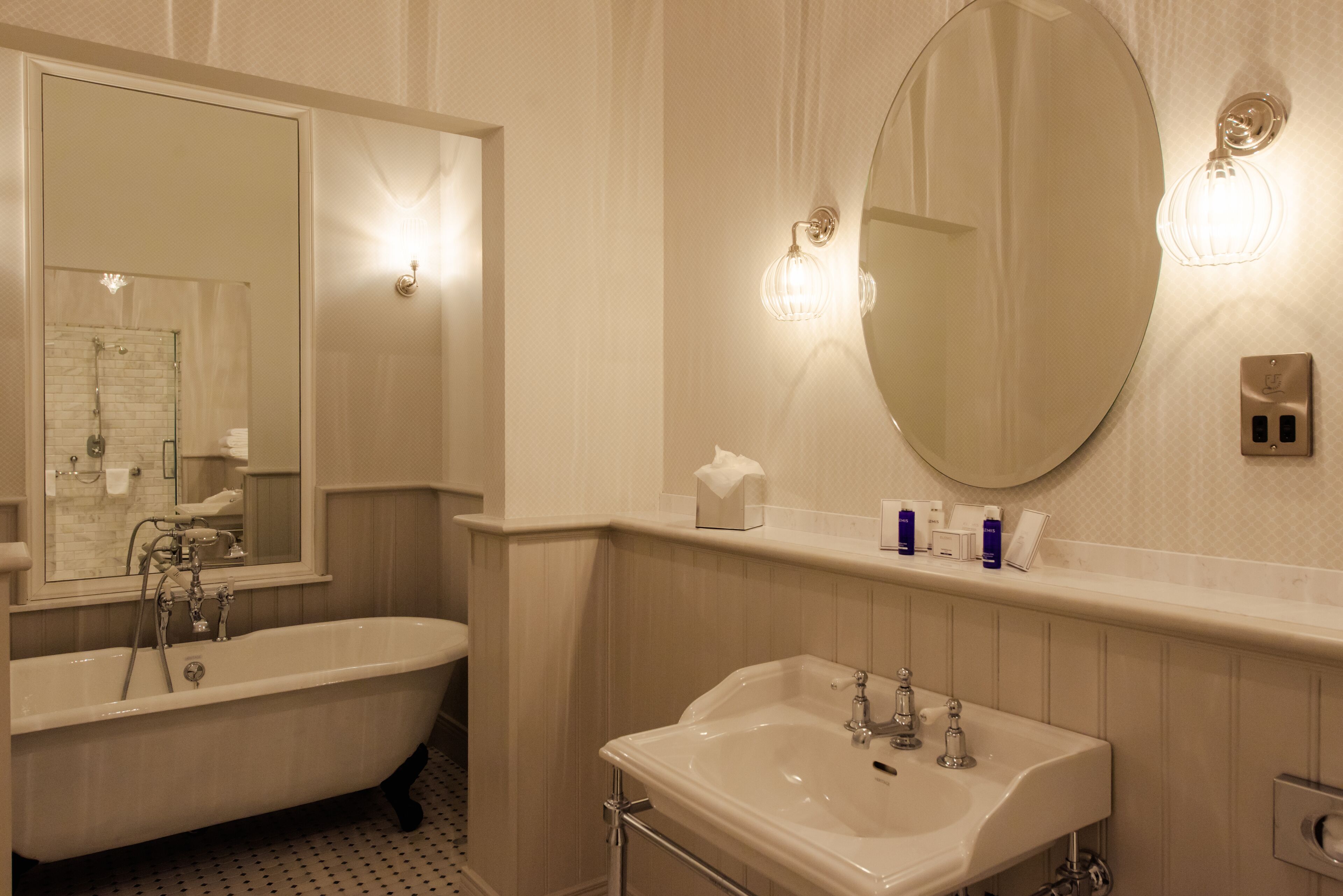 A bathroom with a freestanding bathtub, a sink, and a large mirror.