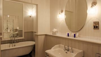 Un baño con una bañera independiente, un lavamanos y un espejo grande.