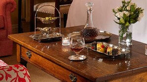 Una mesa de madera con una bandeja de fruta, una jarra y un florero.