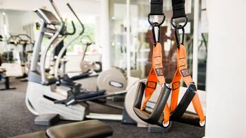 A gym with exercise equipment including treadmills, a bench, and TRX suspension straps.