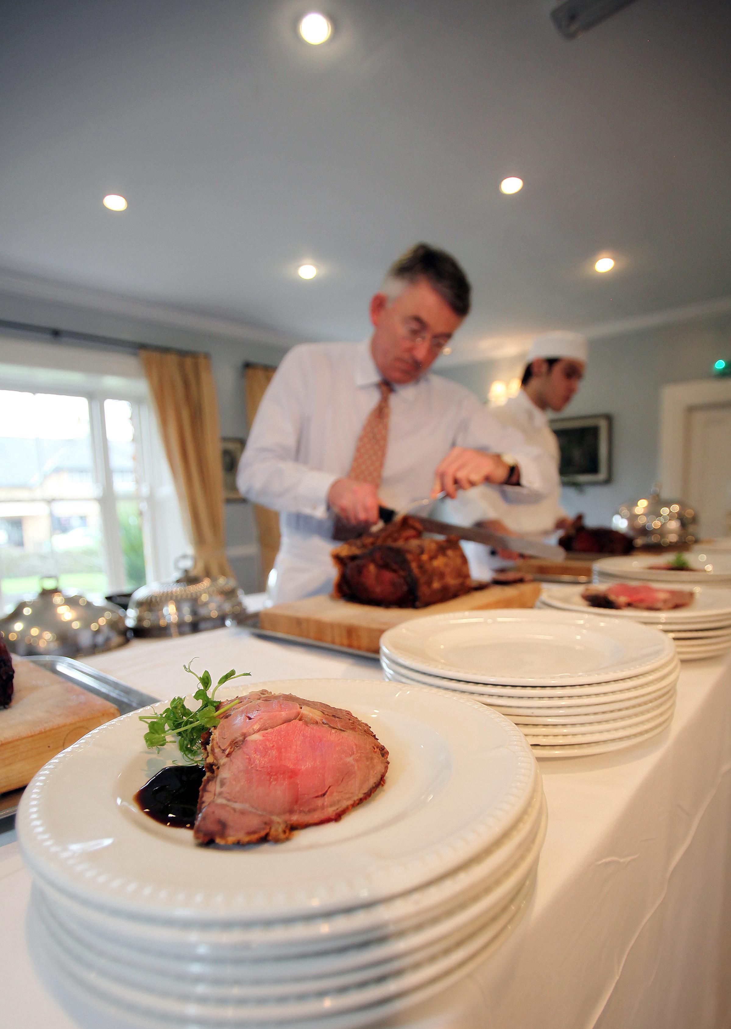 A dining area with a long table set for a meal, featuring plates of food and a chef preparing dishes.