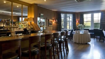 A bar area with stools, a counter with bottles, and a table with chairs.